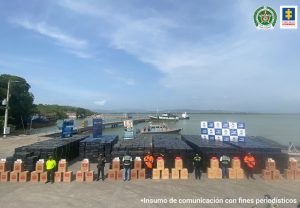 En la imagen se aprecia varias cajas envueltas en plástico negro en las que están empacados cigarrillos de contrabando. Al fondo varias embarcaciones, en una de las cuales era transportado el cargamento.