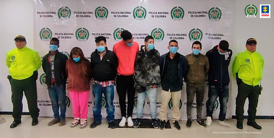 En la fotografía se observa a los 8 capturados junto a dos agentes de la Policía Nacional. En la parte superior se observa un banner de la Policía Nacional.