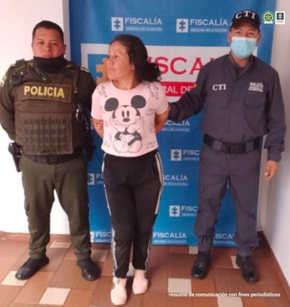En la fotografía se observa a la capturada junto a un servidor del CTI. En la parte superior se observa un banner de la Fiscalía General de la Nación
