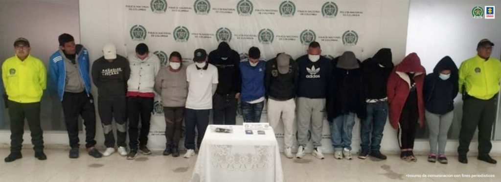 En la fotografía se observa los 13 capturados junto a dos agentes de la Policía Nacional. En la parte superior se observa un banner de la Policía