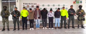 En la fotografía se observa a los 6 detenidos junto a dos soldados del ejército Nacional y dos agentes de la Policía Nacional. En la parte superior se observa un banner de la Policía Nacional y otro banner del Guala Militar