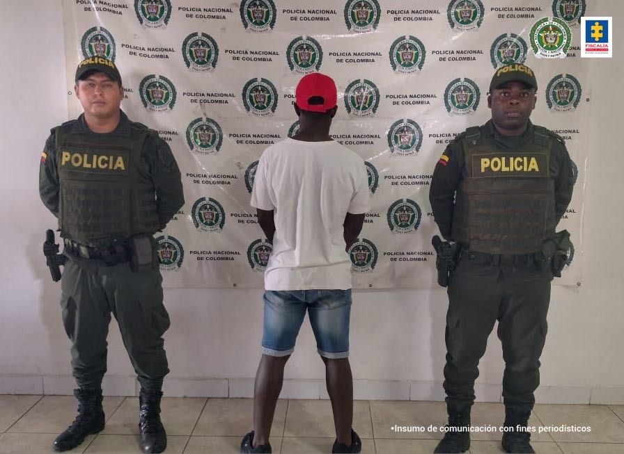 En la fotografía se observa al capturado junto a dos agentes de la Policía Nacional. En la parte superior se observa un banner de la Policía Nacional