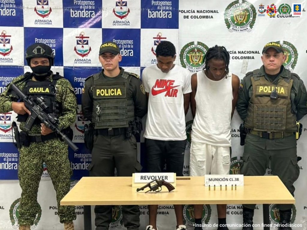 En la fotografía se observa los dos capturados junto a dos agentes de la Policía. En la parte superior se observa un banner de la Policía Nacional