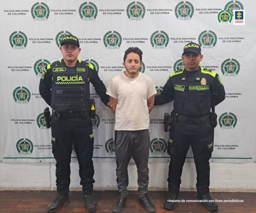 en la foto el procesado acompañado de dos unifmrados atrás un baking de la policía nacional