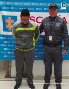 En la fotografía se observa al capturado junto a un servidor del CTI. En la parte superior se observa un banner de la Fiscalía General de la Nación