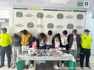 En la foto los procesados capturados vigilados por uniformados de la policía, al frente una mesa conelementos incautoados a los capturados