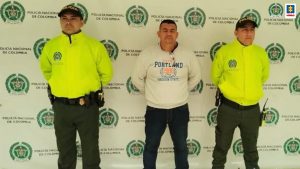 En la fotografía aparece el capturado junto a dos agentes de la Policía Nacional. En la parte superior está un banner de la Policía Nacional 