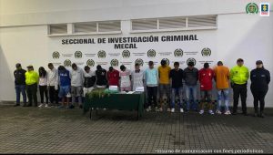 En la fotografía aparecen en fila los capturados junto a servidores del CTI de la Fiscalía y agentes de la Policía Nacional. En la parte posterior está una mesa sobre ella papeletas de marihuana.  