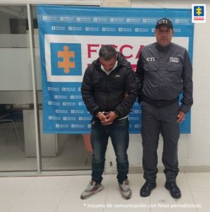 En la fotografía aparece el capturado junto a un servidor del CTI. En la parte superior está un banner de la Fiscalía