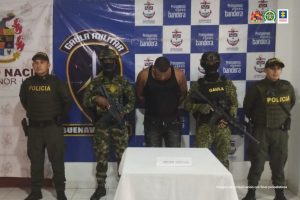 En la fotografía aparece el capturado junto a dos agentes de la Policía Nacional y dos soldados del Gaula Militar. En la parte superior está un banner del Ejército Nacional y del Gaula Militar
