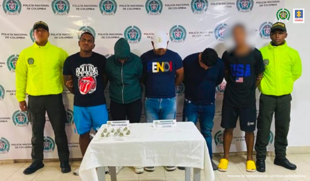 En la fotografía aparecen los 4 asegurados junto a dos agentes de la Policía Nacional. En la parte posterior está un banner de la Policía Nacional