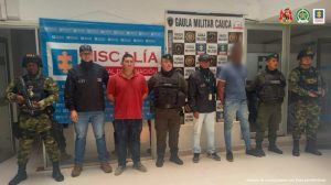 En la fotografía aparecen los dos capturados junto con dos servidores del CTI, dos agentes del Goes de la Policía y dos soldados del Gaula Militar. En la parte superior están un banner de la Fiscalía General y otro del Gaula Militar