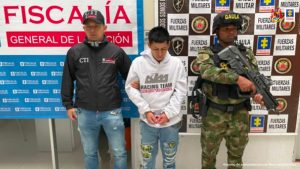 En las fotografías aparecen los capturados junto a dos agentes del Gaula de la Policía Nacional. En la parte superior se observa un banner de la Fiscalía General de la Nación y un banner del Gaula Militar