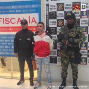 En las fotografías aparecen los capturados junto a dos agentes del Gaula de la Policía Nacional. En la parte superior se observa un banner de la Fiscalía General de la Nación y un banner del Gaula Militar