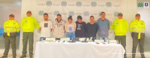 En la fotografía aparecen los seis capturados junto a cuatro agentes de la Policía. En la parte posterior está una mesa con armas de fuego, munición, explosivos y teléfonos celulares
