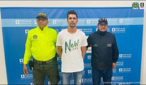 En la foto aparece Gelcinei Soares de Oliveira, alias Yeo o Brasil, a sus lados están dos funcionarios, uno del CTI de la Fiscalía y otro de la Policía Nacional, atrás el pendón con con logos de la Fiscalía.