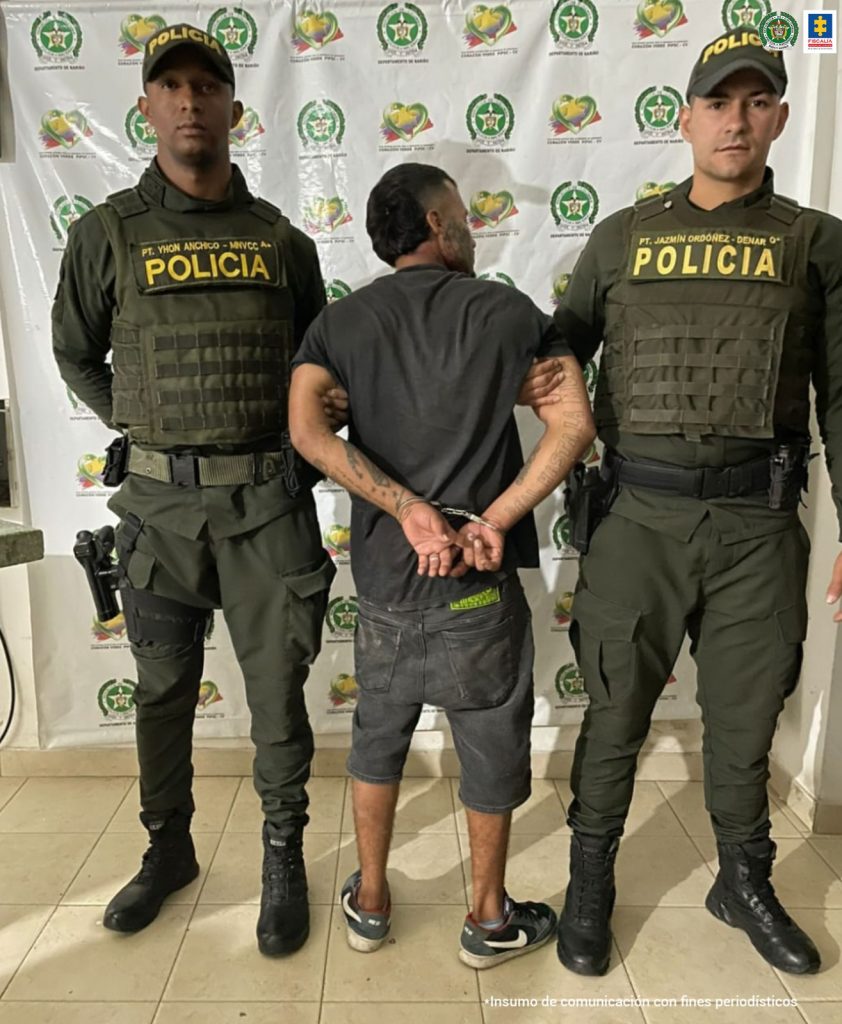 En la fotografía aparece el capturado junto a dos agentes de la Policía Nacional.  En la parte superior está un banner de la Policía Nacional 