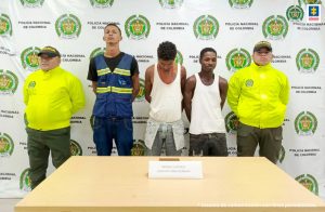 En la fotografía aparecen los tres capturados junto a dos agentes de la Policía Nacional. En la parte superior está un banner de la Policía Nacional