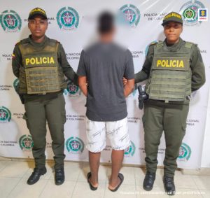 En la fotografía aparece el capturado junto a dos agentes de la Policía Nacional. En la parte superior está un banner de la Policía Nacional