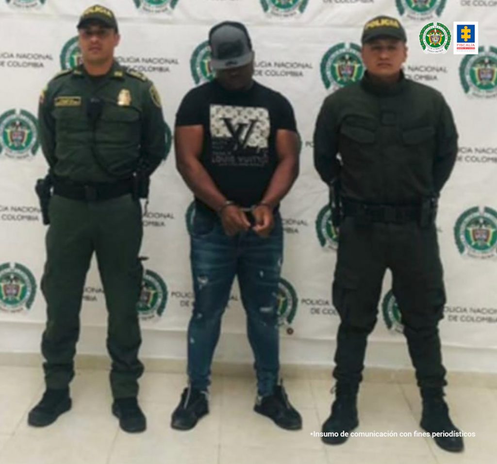 En la fotografía aparece el capturado junto a dos agentes de la Policía Nacional. En la parte superior está un banner de la Policía Nacional 