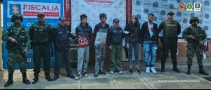 En la fotografía aparecen los cuatro capturados junto a dos servidores del CTI, dos agentes de la Policía Nacional y dos soldados del Ejército. En la parte superior está un banner de la Policía Nacional, un banner del Ejército Nacional y un banner de la Fiscalía General
