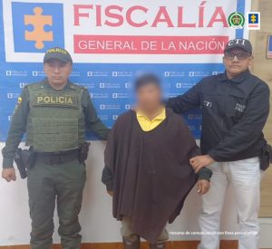 En la fotografía aparece el capturado junto a un servidor del CTI y un agente de la Policía Nacional. En la parte superior está un banner de la Fiscalía General de la Nación