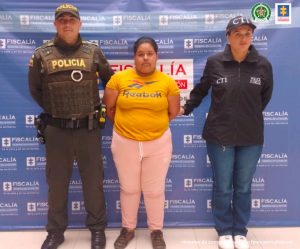 En la fotografía aparece la capturada junto a una servidora del CTI y un agente de la Policía Nacional. En la parte superior está un banner de la Fiscalía General de la Nación
