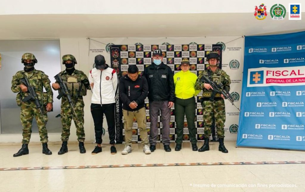 En la fotografía aparecen los tres capturados junto a un servidor del CTI, un agente de la Policía Nacional y tres soldados del Ejército Nacional. En la parte superior están un banner de la Fiscalía General, un banner de las Fuerzas Militares y un banner de la Policía Nacional.