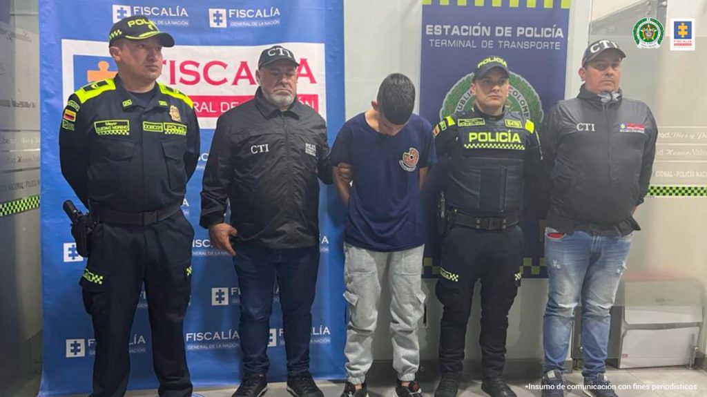 En la fotografía aparece el capturado junto a un servidor del CTI y un agente de la Policía Nacional. En la parte superior está un banner de la Fiscalía General de la Nación
