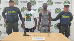 En las fotografías aparecen los dos capturados junto a dos agentes de la Policía Nacional. En la parte posterior está un mesa con un arma de fuego, un proveedor y munición