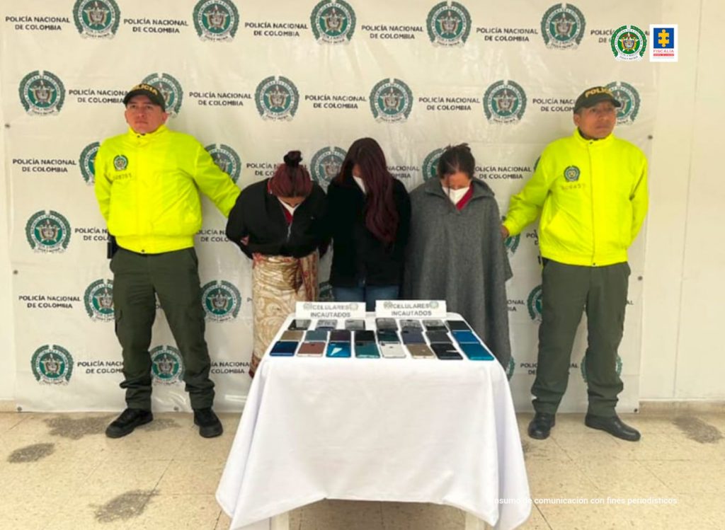 En la fotografía aparecen las capturadas junto a dos agentes de la Policía Nacional. En la parte posterior está una mesa 23 teléfonos celulares recuperados