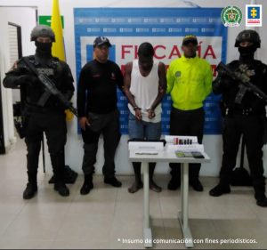 En la fotografía aparece el capturado junto a un servidor del CTI y tres agentes de la Policía Nacional. En la parte posterior está una mesa con teléfonos celulares y munición.