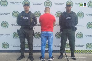 En la fotografía aparece el capturado junto a dos agentes de la Policía Nacional. En la parte superior está un banner de la Policía Nacional