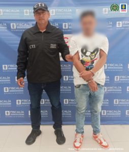 En las fotografía aparece el capturado junto a un servidor del CTI. En la parte superior está un banner de la Fiscalía General de la Nación