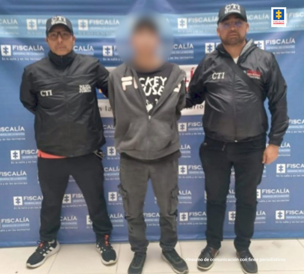 En la fotografía aparece el capturado junto a dos servidores del CTI. En la parte superior se observa un banner de la Fiscalía General