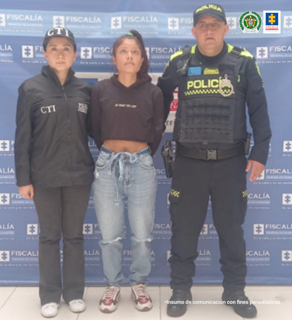 En la fotografía aparece la capturada junto a una servidora del CTI y un agente de la Policía Nacional. En la parte superior está un banner de la Fiscalía General