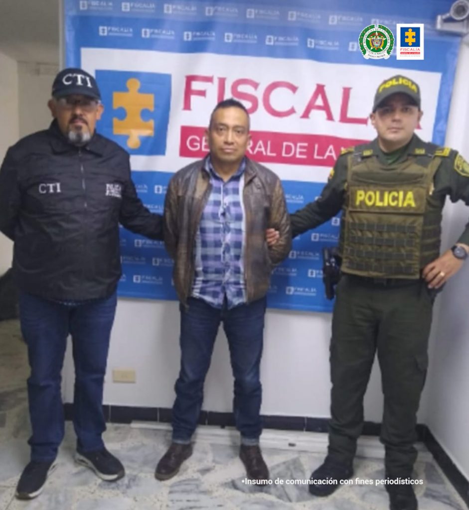 En la fotografía aparece el capturado junto a un servidor del CTI y un agente de la Policía Nacional. En la parte superior está un banner de la Fiscalía General