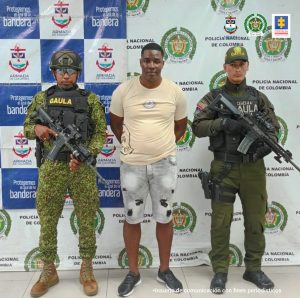 En la fotografía aparece el capturado junto a un agente del Gaula Militar y otro agente del Gaul la Policía Nacional. En la parte superior están un banner de la Policía Nacional y otro banner del Gaula Militar