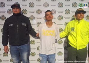 En la fotografía aparece el capturado junto a un servidor del CTI y una agente de la Policía Nacional. En la parte superior está un banner de la Policía Nacional