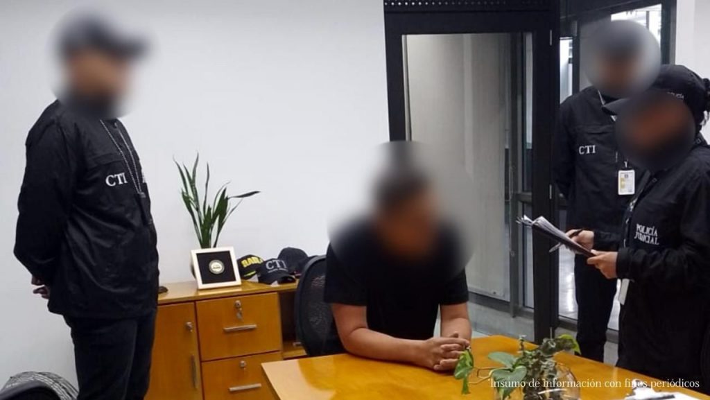 El capturado Francisco Javier Martínez Ardila, está sentado en una mesa rodeado de tres agentes del CTI en el momento de su captura.