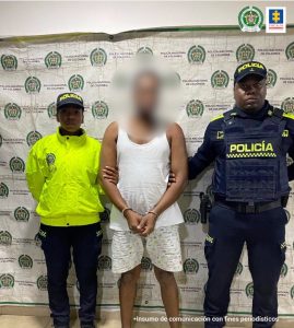 Jaiser David Mosquera Díaz acompañado de funcionarios del Cuerpo Técnico de Investigación CTI de la Seccional Chocó y la Policía Nacional. Atrás el pendón de la Policía.