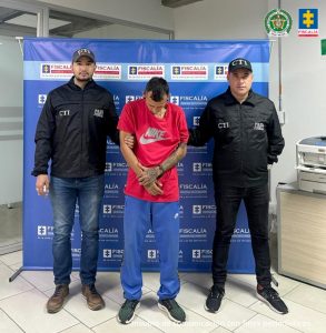 José Alejandro Velásquez Medina, alias Sancocho, acompañado por funcionarios del Cuerpo Técnico de Investigación (CTI) de la Seccional Caldas y de fondo el pendón de la Fiscalía.
