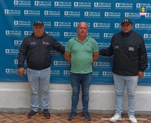 Salomón Herrera Giraldo en la foto acompañado por dos funcionarios del CTI. Detrás el pendón de la Fiscalía.