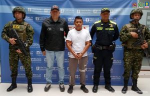 En la fotografía aparece el sentenciado junto a un servidor de CTI, un agente de la Policía Nacional y dos soldados del Ejército Nacional. En la parte superior está un banner de la Fiscalía General de la Nación