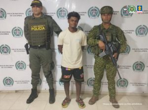 En la fotografía aparece el capturado junto a un agente de la Policía Nacional y un infante de la Armada Nacional. En la parte superior está un banner de la Policía Nacional