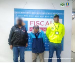 en la foto se observa un hombre con la cara agachada al lado un uniformado de la policía y al otro uno del CTI