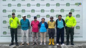 Los imputados se encuentra en custodia por dos uniformados de la Policía Nacional. Detrás se observa un backing de la Policía.