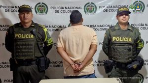 En la fotografía se ve de espaldas un hombre, identificado como Yerlín Andrey Giraldo Marín, integrante de la UNP, en compañía de uniformados de la Policía Nacional