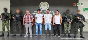 Se visualiza a cuatro de los capturados junto a uniformados del Gaula del Ejército y Policía Nacional. Detrás de ellos un banner que identifica a la Policía Nacional.