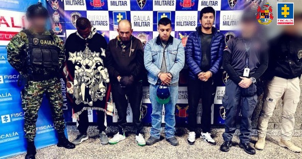 en la fotografia se puede ver a los 4 judicializados en medios de funcionarios del ejercicito y el gaula, detras de ellos se encuentra un baking del Gaula